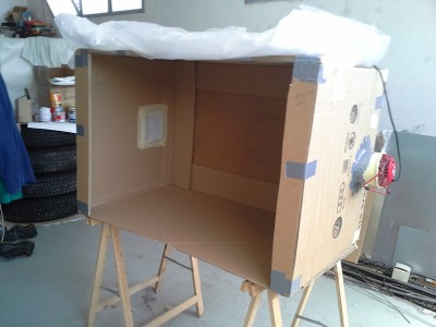 Cabina de pintura fabricada a partir de una caja de cartón, dos ventilardores para meter aire y filtros de polvo una bolsa de plástico y cinta americana. La idea es crear una corriente de aire hacia el exterior de la caja que evite que se cuele el polvo del ambiente.