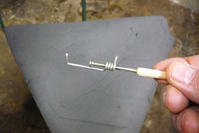 Uno de los sargentos visto al detalle. Son una variante de los sargentos que me enseñó a hacer nuestro amigo José Rodríguez, salvo que éstos los hago con alambre galvanizado de 2 mm. de diámetro, ya que, los que me enseñó a hacer José, es con varilla cuadrada de 4x4 mm. y esta medida no me coge entre las cuadernas.<br />El arrollamiento del alambre, lógicamente, está roscado a M3, aunque previamente lo estañe para que cogiera más resistencia.  Los sargentos parecen débiles, pero permiten hacer una presión de 1,5 kg. Suficiente para lo que son.