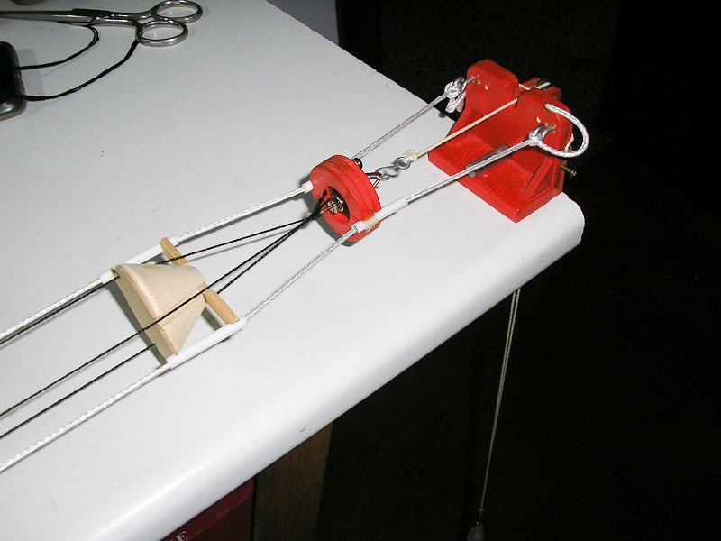 A la izquierda el separador de los tres cordones; en el centro, el disparador de giro libre y a la derecha el anclaje de los cabos guía; incorpora una roldana para el tensor de trabajo.
