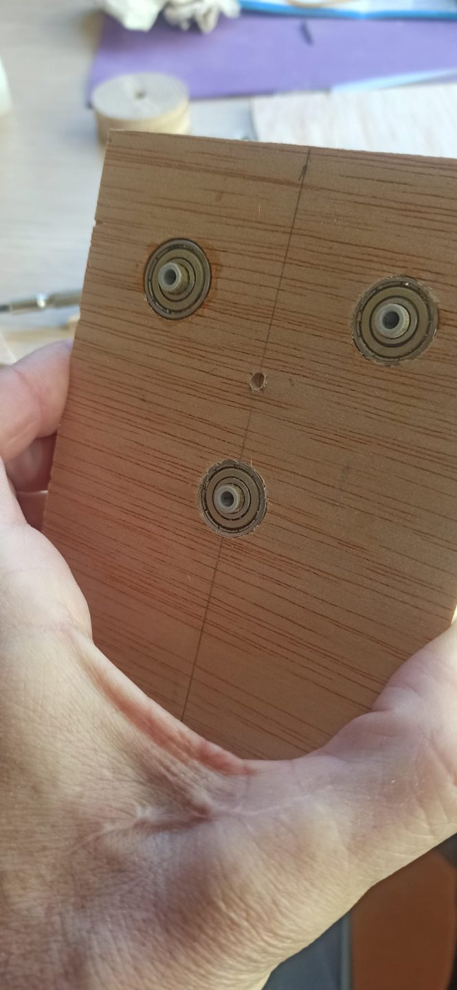 Cortadas dos tablas de la  medida del boceto, las encolo para darle grosor, taladro a 17mm diámetro y distancia de 50 para insertar por presión los rodamientos de los chinos, con agujero central de 6 mm donde inserto un tuvo de latón suficientemente largo apra por el otro extremo colocar la polea de madera, previamente taladrada y habiendole hecho un rebaje semicircualar para la justa torica que hara de correa