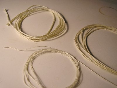 En la parte inferior el hilo de mercería utilizado.
<br />A la derecha un colchado con cuatro hilos y arriba un cabo colchado con cuatro cordones de dos hilos cada uno.