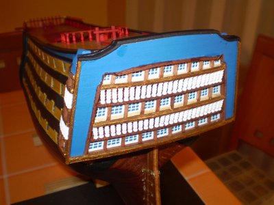 Con un listón de ramín de 2 x 3 mm lo cortaremos ajustado a la medida y aremos los posa brazos de las balconadas dándole su curvatura los pintaremos y los pegaremos con pegamento de secado rápido, y pintaremos los remates exteriores del espejo de popa.