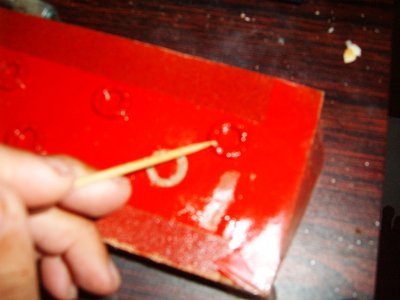 remuevo la pintura roja con la punta de un palillo, de la cabeza de alfiler, que hace las veces de remache...
