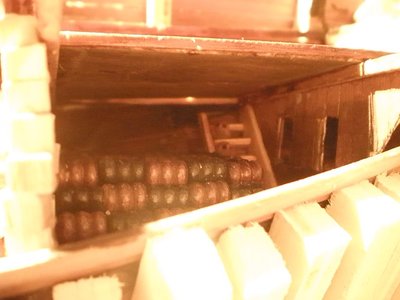 El mamparo del pañol de encartuchado tiene dos aberturas para acceso al pañol de los estantes y  desde este al de la pólvora.
