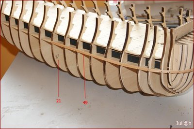 Seguidamente procedemos a forrar el casco. Partiendo de la mitad de la cuaderna Nº21 hacia proa y a la altura de la primera cubierta, encolamos y clavamos una traca de forro (listón 2 x 5 mm de Tilo), luego colocamos otra hacia popa.